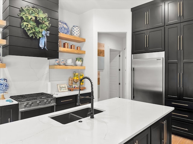 kitchen with light wood-type flooring, sink, high end appliances, backsplash, and light stone countertops