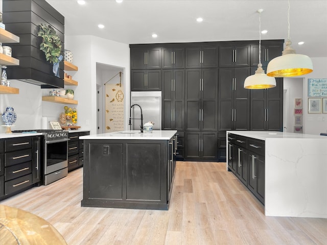 kitchen featuring sink, hanging light fixtures, light hardwood / wood-style flooring, a center island with sink, and appliances with stainless steel finishes