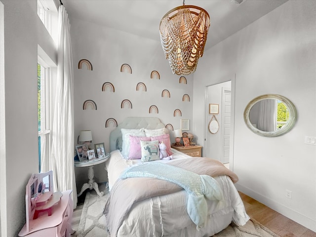 bedroom featuring an inviting chandelier, light wood-type flooring, and multiple windows