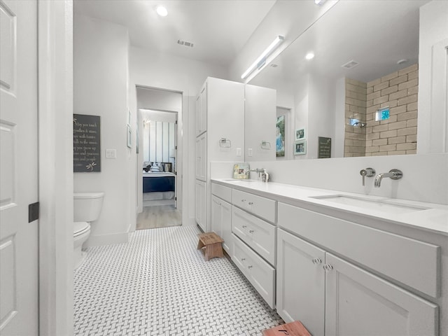 bathroom featuring a tile shower, vanity, and toilet