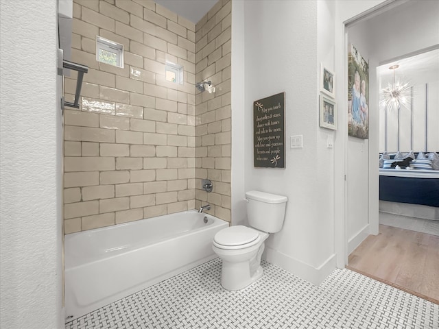 bathroom featuring tiled shower / bath, hardwood / wood-style floors, and toilet