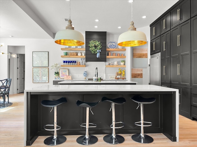 bar featuring built in fridge, light hardwood / wood-style floors, and decorative light fixtures