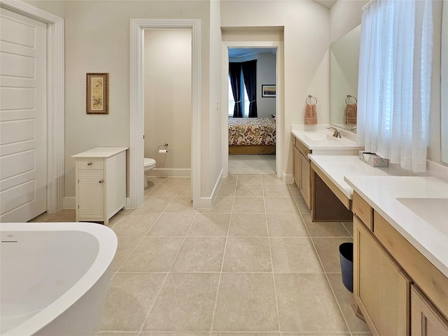 bathroom with tile patterned floors, vanity, toilet, and a tub to relax in