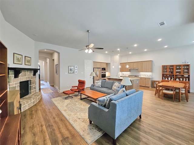 living room featuring ceiling fan, light hardwood / wood-style floors, and a fireplace