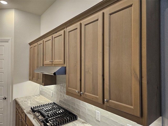 kitchen with tasteful backsplash, light stone counters, and gas stovetop