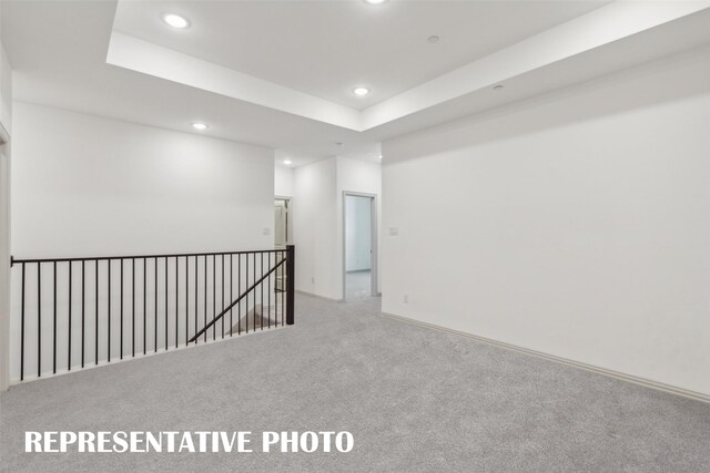 carpeted spare room with a tray ceiling