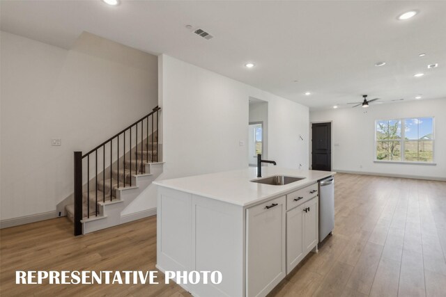 kitchen with light hardwood / wood-style flooring, an island with sink, white cabinetry, and sink