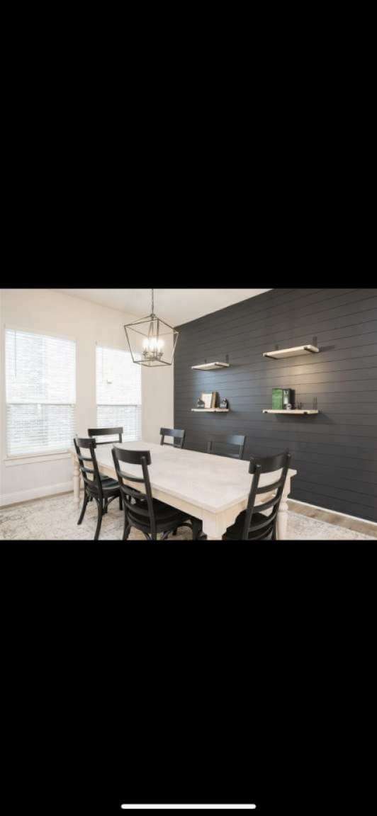 dining space with an inviting chandelier and wooden walls