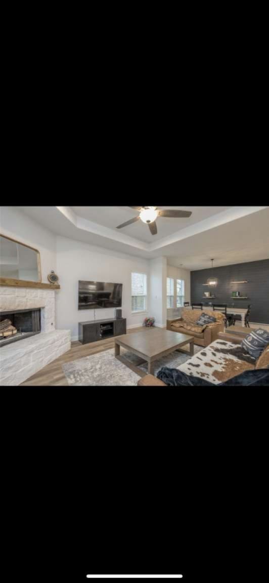 unfurnished living room featuring ceiling fan, wood-type flooring, and a tray ceiling