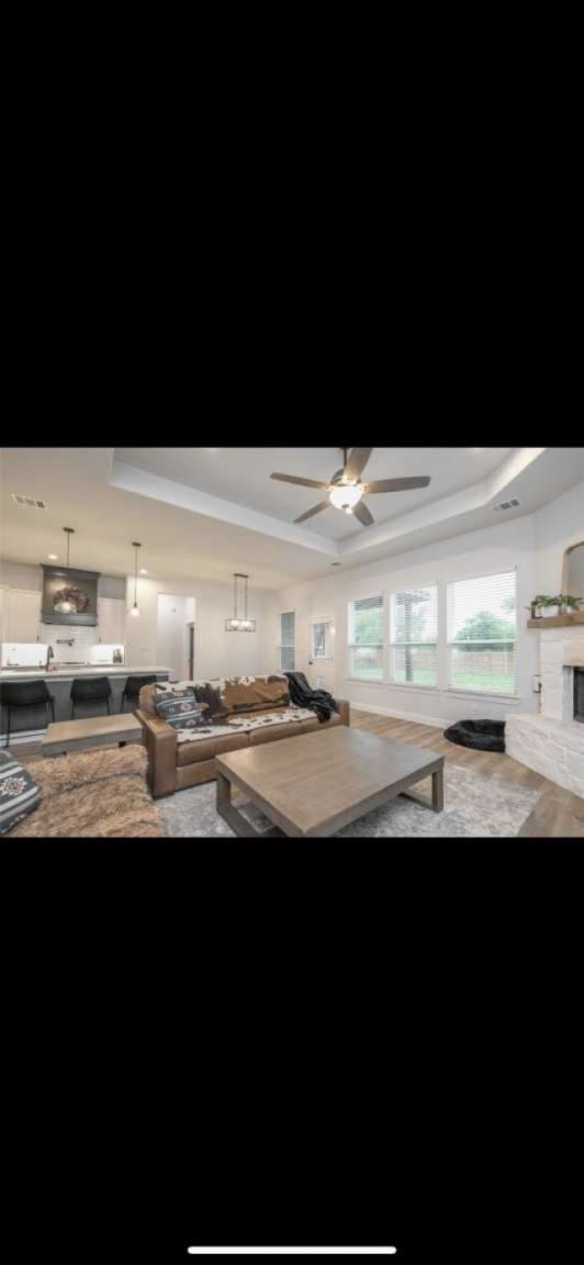 kitchen featuring a tray ceiling, a brick fireplace, and ceiling fan