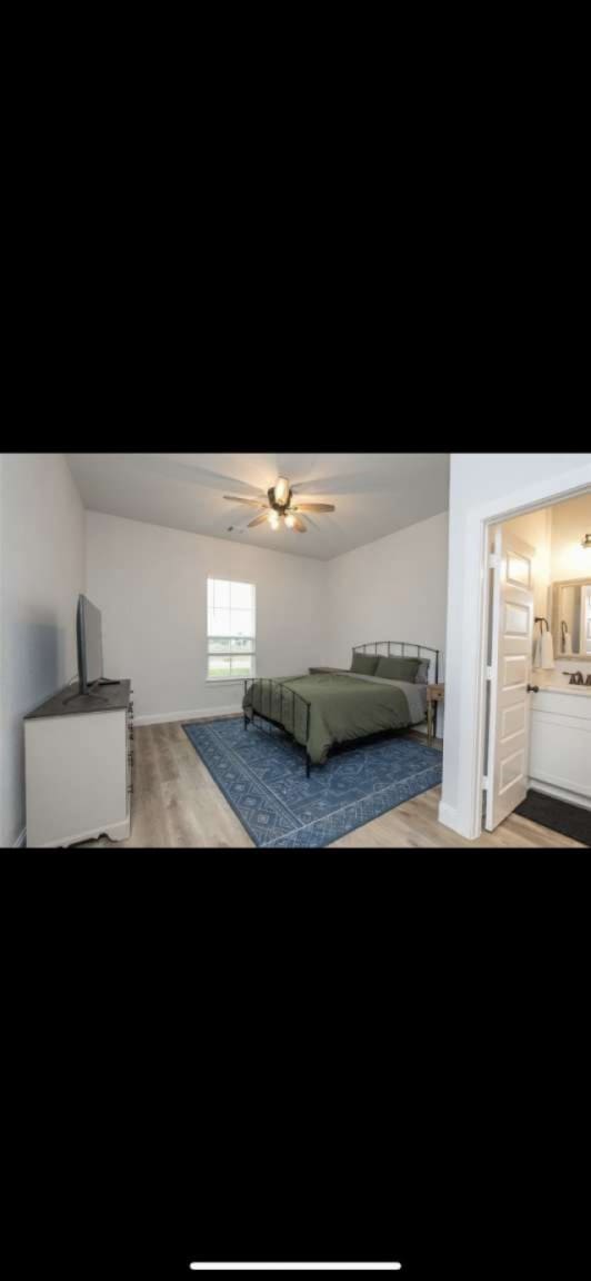 bedroom with light hardwood / wood-style flooring, ceiling fan, and connected bathroom