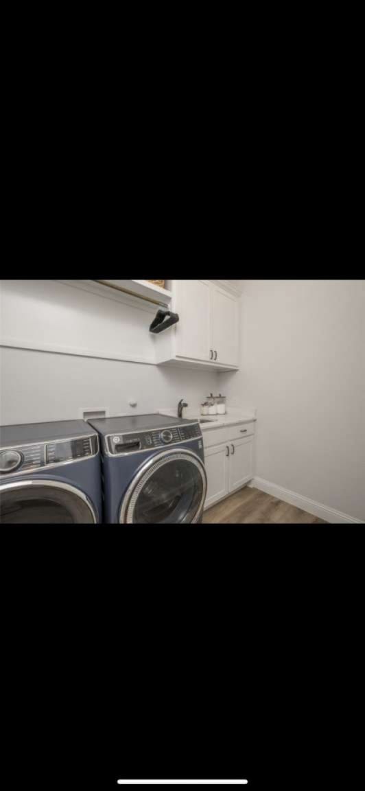 clothes washing area featuring washer and clothes dryer, wood-type flooring, cabinets, and sink