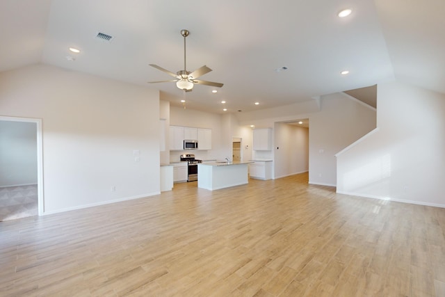 unfurnished living room featuring lofted ceiling, sink, light wood-type flooring, and ceiling fan