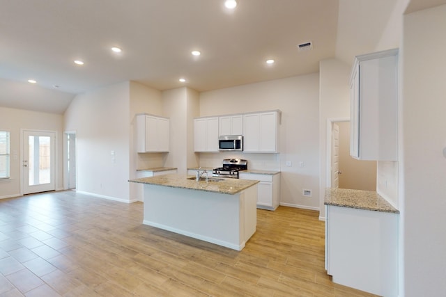 kitchen featuring appliances with stainless steel finishes, white cabinetry, light stone counters, and sink