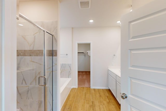 bathroom with hardwood / wood-style floors, plus walk in shower, and vanity