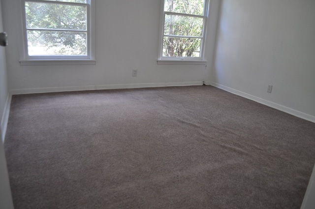 unfurnished room with a healthy amount of sunlight and dark carpet