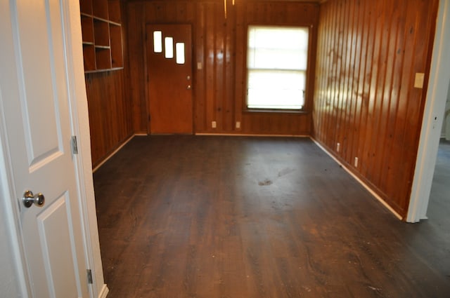 unfurnished room featuring dark wood-type flooring and wooden walls