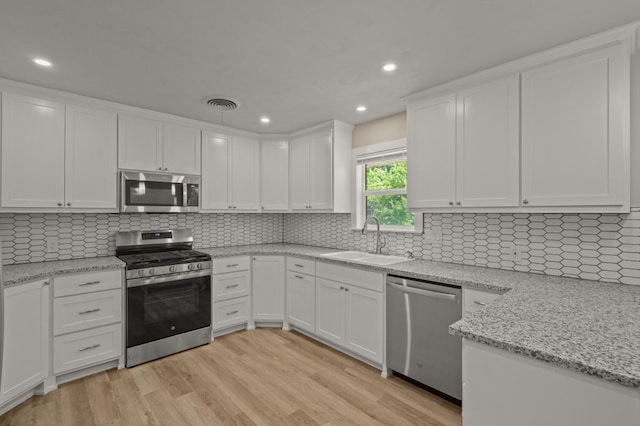 kitchen with light wood-type flooring, sink, appliances with stainless steel finishes, and white cabinets