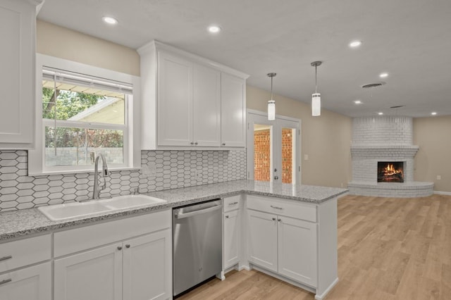 kitchen featuring dishwasher, sink, white cabinets, and a fireplace