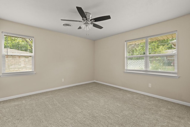 empty room featuring carpet flooring, ceiling fan, and a healthy amount of sunlight