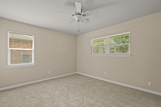 carpeted empty room with a wealth of natural light and ceiling fan