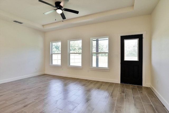 foyer entrance with a tray ceiling, ceiling fan, and light hardwood / wood-style floors