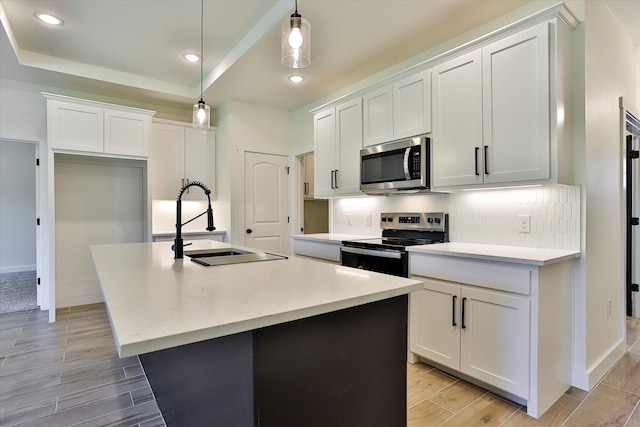 kitchen featuring light hardwood / wood-style floors, appliances with stainless steel finishes, pendant lighting, and an island with sink