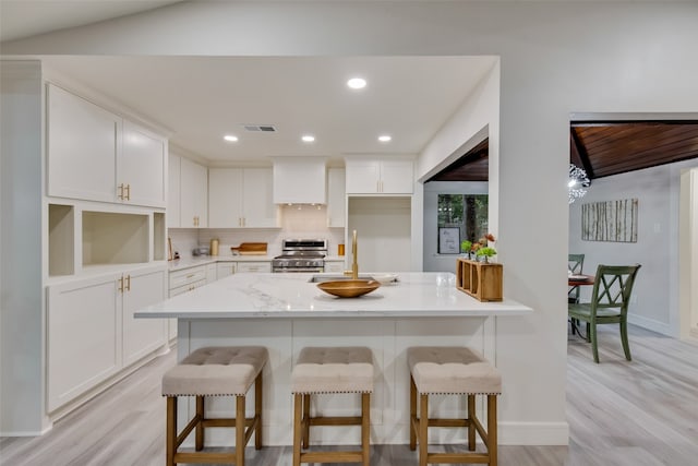 kitchen with white cabinets, a breakfast bar, sink, and stainless steel range