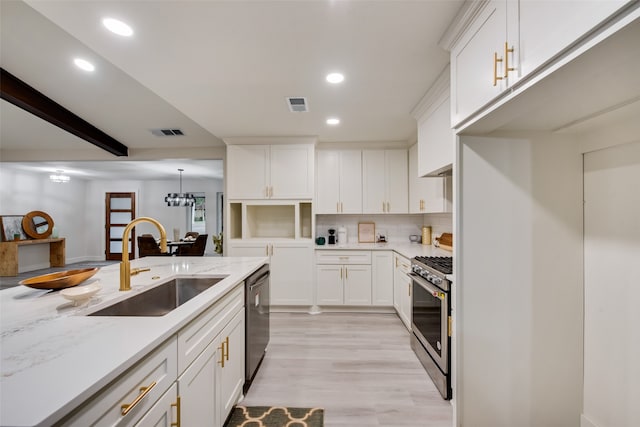 kitchen with pendant lighting, sink, white cabinets, and stainless steel appliances