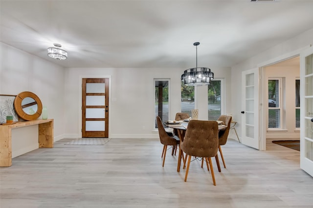 dining area featuring a chandelier, french doors, and light hardwood / wood-style flooring