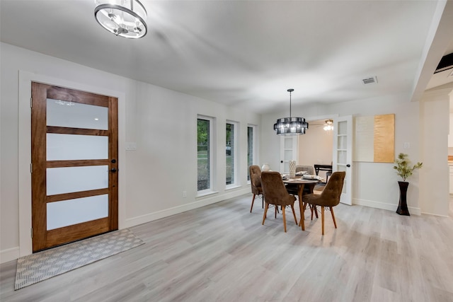 dining space featuring light hardwood / wood-style flooring and an inviting chandelier