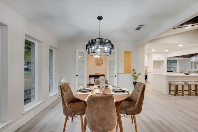 dining space with light hardwood / wood-style flooring and a chandelier