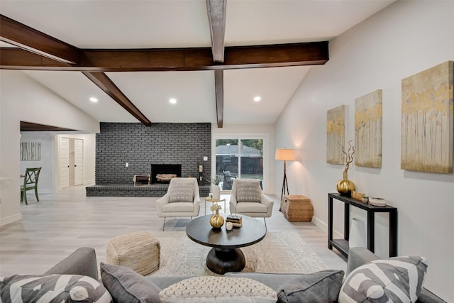 living room with vaulted ceiling with beams, light hardwood / wood-style floors, and a brick fireplace