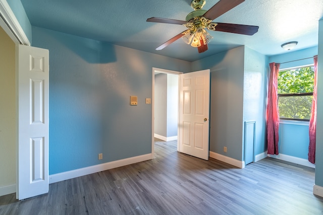 unfurnished bedroom featuring ceiling fan, a textured ceiling, and wood-type flooring