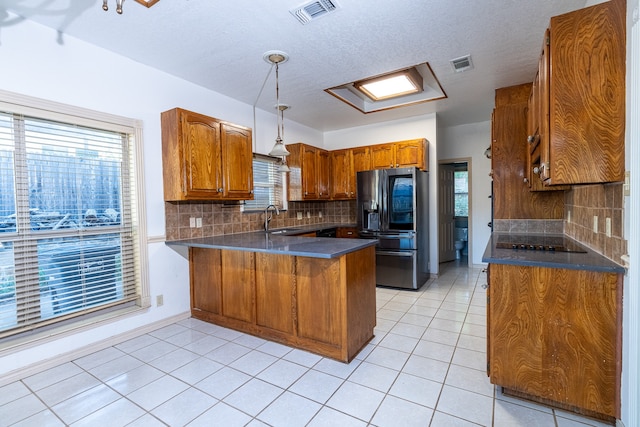 kitchen featuring stainless steel refrigerator with ice dispenser, kitchen peninsula, a healthy amount of sunlight, and sink