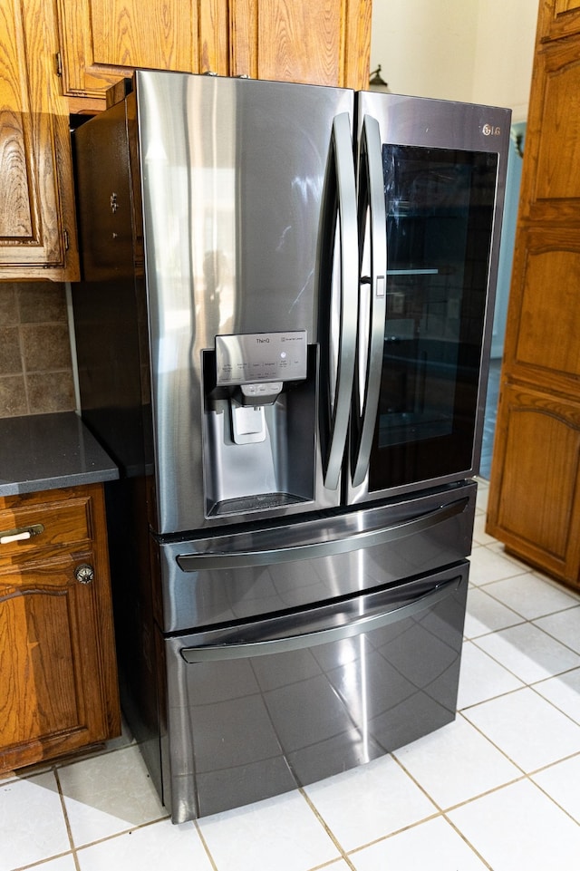 kitchen with stainless steel fridge, light tile patterned floors, and decorative backsplash