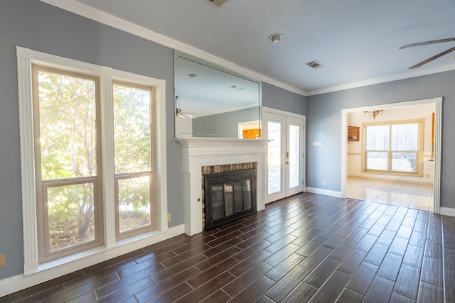 unfurnished living room featuring ceiling fan, a brick fireplace, and ornamental molding