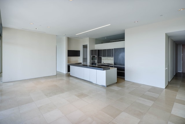 kitchen featuring light tile patterned flooring, a kitchen island, and backsplash