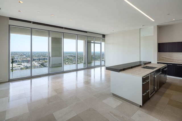 kitchen with sink, a kitchen island with sink, and light tile patterned floors