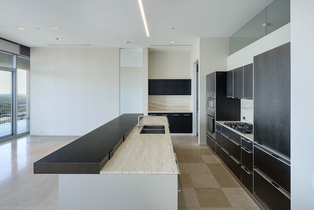 kitchen featuring stainless steel gas cooktop, light tile patterned flooring, sink, and a kitchen island