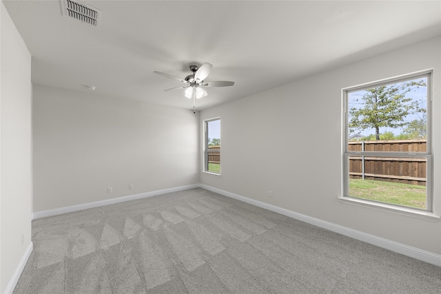 unfurnished room with ceiling fan, light carpet, and a wealth of natural light