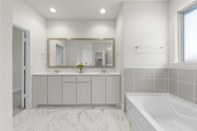 bathroom featuring plenty of natural light, vanity, and a tub