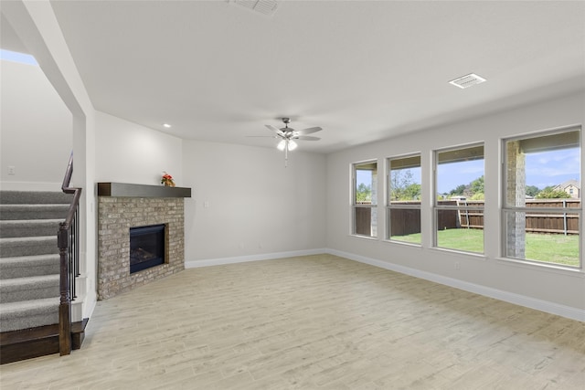 unfurnished living room featuring ceiling fan, light wood-type flooring, and a fireplace