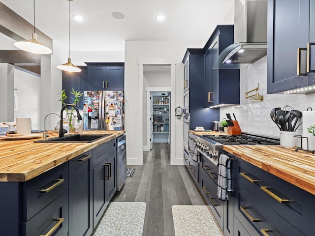 kitchen with pendant lighting, sink, wall chimney range hood, dark hardwood / wood-style flooring, and wood counters