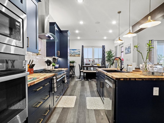 kitchen featuring appliances with stainless steel finishes, hanging light fixtures, wooden counters, and plenty of natural light