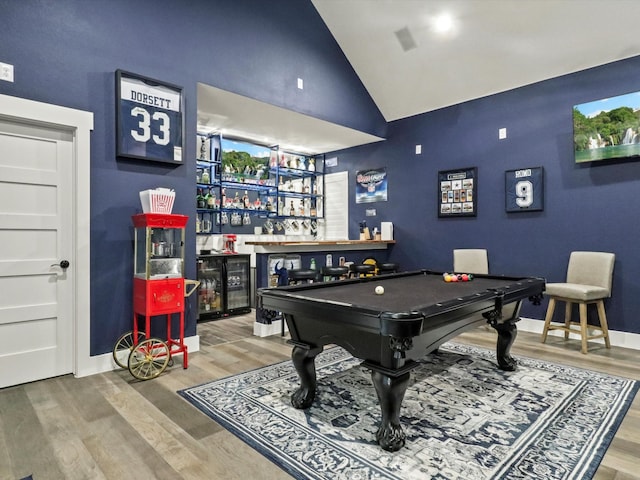 game room with hardwood / wood-style floors, bar, pool table, and high vaulted ceiling