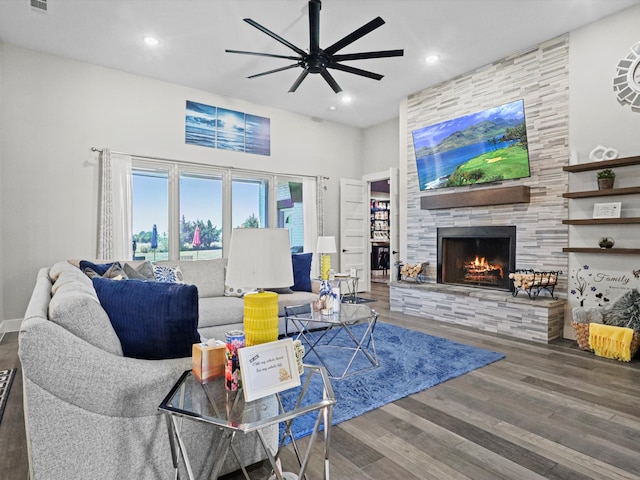 living room with a stone fireplace, ceiling fan, and hardwood / wood-style flooring