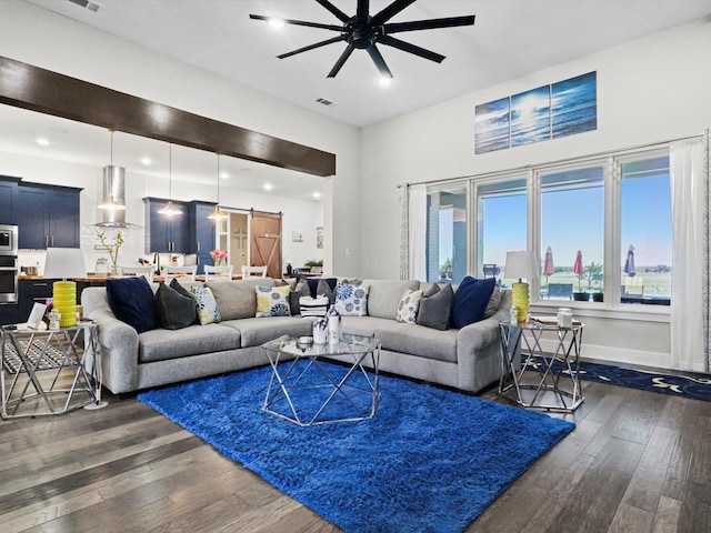 living room featuring ceiling fan, dark hardwood / wood-style floors, and a barn door