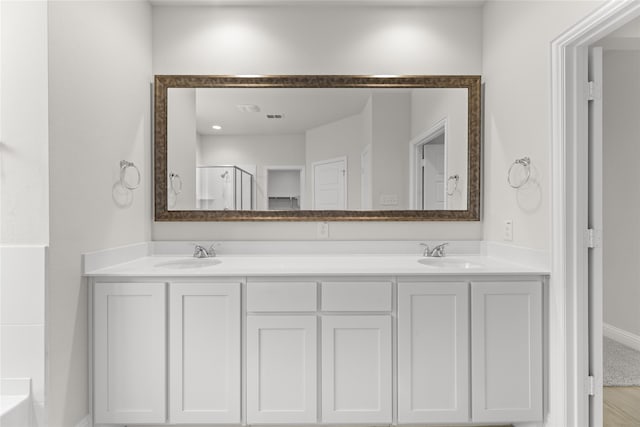 bathroom featuring a shower with door and vanity