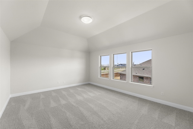 additional living space featuring vaulted ceiling and carpet flooring